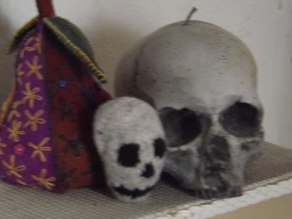 photo of embroidered pear, knitted human skull, candle in the shape of a human skull